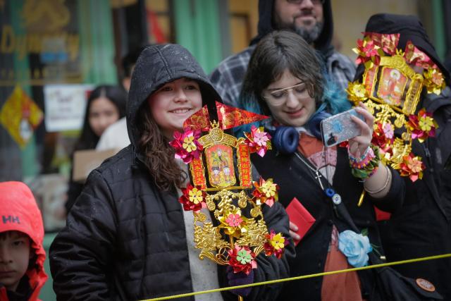 (260223) -- VANCOUVER, Feb. 23, 2026 (Xinhua) -- People carry Chinese New Year-themed ornaments while watching a Spring Festival parade at Chinatown in Vancouver, British Columbia, Canada, on Feb. 22, 2026. The 52nd annual Vancouver Chinatown Spring Festival Parade was held here on Sunday to celebrate the Chinese Year of the Horse. (Photo by Liang Sen/ Xinhua)