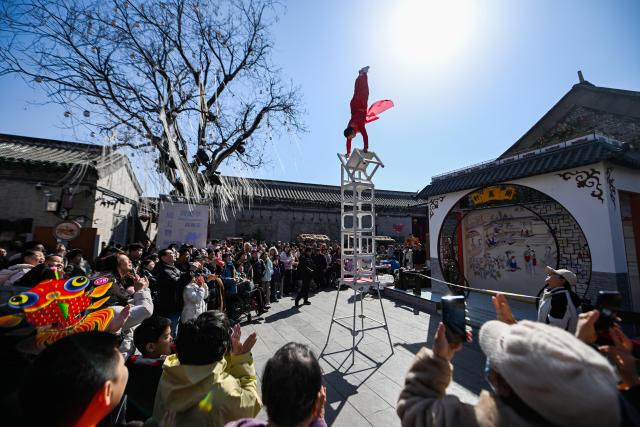 (260223) -- BEIJING, Feb. 23, 2026 (Xinhua) -- Visitors watch an acrobatic show at Yangliuqing ancient town in Tianjin, north China, Feb. 22, 2026. Yangliuqing ancient town launched a range of activities featuring folk customs, traditional culture and interactive experiences, offering visitors an immersive folk feast during this Spring Festival holiday. (Xinhua/Zhao Zishuo)
