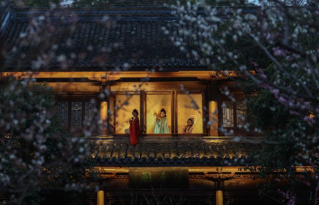 (260223) -- HANGZHOU, Feb. 23, 2026 (Xinhua) -- Tourists play immersive script-based games at Chaoshan scenic area in Hangzhou, east China's Zhejiang Province, Feb. 23, 2026. The scenic area kicked off on Monday a special night tour event among plum blossom trees illuminated by light. (Xinhua/Xu Yu)