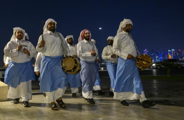 (260224) -- DOHA, Feb. 24, 2026 (Xinhua) -- Traditional Ramadan Musaharati performers walk along the waterfront at the Old Doha Port during the holy month of Ramadan in Doha, Qatar, on Feb. 23, 2026. The Musaharati tradition involves drummers touring neighborhoods at night to wake up the residents for the pre-dawn "suhoor" meal. (Photo by Nikku/Xinhua)