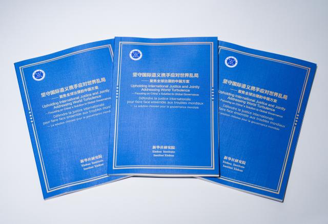 (260224) -- GENEVA, Feb. 24, 2026 (Xinhua) -- This photo shows copies of the think tank report titled "Upholding International Justice and Jointly Addressing World Turbulence -- Focusing on China's Solution to Global Governance." The Xinhua Institute, a think tank affiliated with Xinhua News Agency, on Tuesday released a report titled "Upholding International Justice and Jointly Addressing World Turbulence -- Focusing on China's Solution to Global Governance" at the Palais des Nations in Geneva. (Xinhua/Shi Feng)