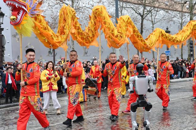 (260224) -- PARIS, Feb. 24, 2026 (Xinhua) -- Performers led by a humanoid robot take part in a parade celebrating the Chinese New Year on the Champs-Elysees avenue in Paris, France, on Feb. 1, 2026. TO GO WITH "Roundup: Future-oriented Chinese New Year in France blends tradition, technology" (Xinhua/Zhang Baihui)