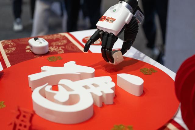 (260225) -- BEIJING, Feb. 25, 2026 (Xinhua) -- A humanoid robot grabs a piece of tofu at an event in Wuhan, central China's Hubei Province, Feb. 24, 2026. (Xinhua/Xiao Yijiu)