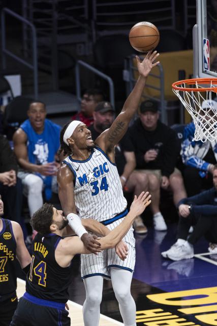 (260225) -- LOS ANGELES, Feb. 25, 2026 (Xinhua) -- Orlando Magic's Wendell Carter Jr. (top) goes for a layup during the 2025-2026 NBA regular season basketball game between Los Angeles Lakers and Orlando Magic in Los Angeles, the United States, Feb. 24, 2026. (Photo by Ringo Chiu/Xinhua)