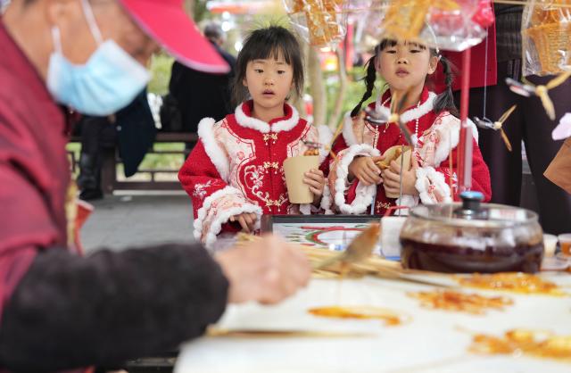 (260227) -- CHENGDU, Feb. 27, 2026 (Xinhua) -- Children watch a syrup art craftsman working at a temple fair at Wuhou Shrine in Chengdu, southwest China's Sichuan Province, Feb. 27, 2026. The temple fair is held here to mark the ongoing Spring Festival, or the Chinese New Year, which will end on the 15th day of the first lunar month. (Xinhua/Liu Kun)