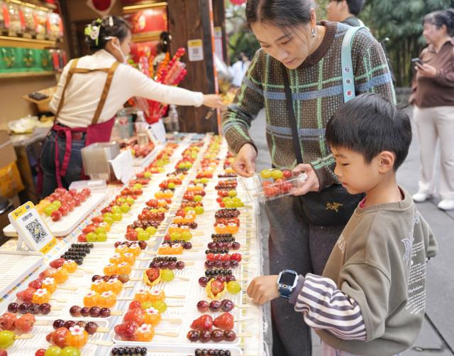 (260227) -- CHENGDU, Feb. 27, 2026 (Xinhua) -- People select sugar-coated fruits at a temple fair at Wuhou Shrine in Chengdu, southwest China's Sichuan Province, Feb. 27, 2026. The temple fair is held here to mark the ongoing Spring Festival, or the Chinese New Year, which will end on the 15th day of the first lunar month. (Xinhua/Liu Kun)