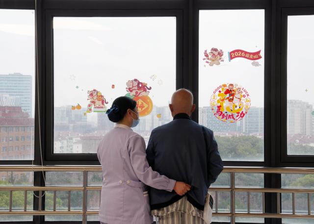(260227) -- SHANGHAI, Feb. 27, 2026 (Xinhua) -- A nursing assistant helps an inpatient walk at a hospital in Shanghai, east China, Feb. 26, 2026. China's hospitals are piloting "companion-free" care services to ease the heavy burden of daily care-giving on the inpatients' families.
  The new mode of operation requires hosting hospitals to directly employ trained nursing assistants to provide 24-hour non-medical care for inpatients with particular needs. 
   Such services used to rely solely on family members of the inpatients or private caregivers they hire. (Xinhua/Liu Ying)