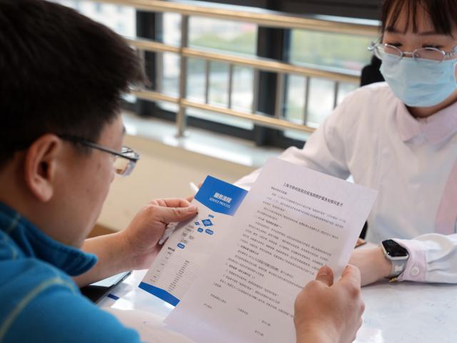 (260227) -- SHANGHAI, Feb. 27, 2026 (Xinhua) -- A family member of an inpatient learns about the "companion-free" care services at a hospital in Shanghai, east China, Feb. 26, 2026. China's hospitals are piloting "companion-free" care services to ease the heavy burden of daily care-giving on the inpatients' families.
  The new mode of operation requires hosting hospitals to directly employ trained nursing assistants to provide 24-hour non-medical care for inpatients with particular needs. 
   Such services used to rely solely on family members of the inpatients or private caregivers they hire. (Xinhua/Liu Ying)