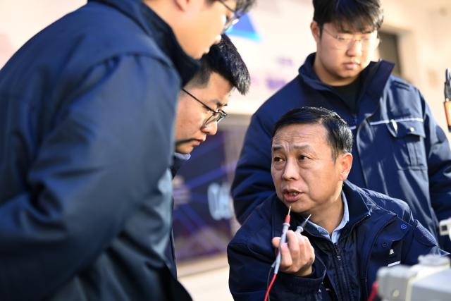 (260227) -- XI'AN, Feb. 27, 2026 (Xinhua) -- Dong Hongtao (front, R) communicates with members of a state-level master technician studio led by him in Xi'an, northwest China's Shaanxi Province, Jan. 14, 2026.
  Dong Hongtao is a bullet train technician of China Railway Xi'an Group Co., Ltd. and a deputy to the National People's Congress (NPC). Since engaging in electric multiple unit (EMU) maintenance work in 2007, Dong has led his team to maintain over 120,000 EMU sets and handled more than 3,000 faults. He has been granted three national invention patents and 31 utility model patents. Dong has also been dedicated to the passing-on of technical skills, cultivating skilled talents for the industry through the national-level master technician studio led by him.
   As a senior technician who started as an ordinary worker, Dong understands the challenges faced by frontline workers in their developments. He has observed that they often have abundant practical experiences but lack theoretical knowledge. In response, he actively participates in initiatives to improve their skills and identifies young talents to foster their creativity.
   For this year's legislative session, Dong said he will continue to focus on the development of the skilled workforce, concentrating on advancing the implementation of the new professional title system, which features eight technical titles -- three more than the previous five-tier system. (Xinhua/Li Yibo)
