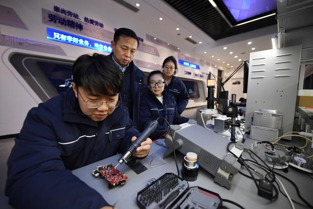 (260227) -- XI'AN, Feb. 27, 2026 (Xinhua) -- Dong Hongtao (2nd L) tutors a member of a state-level master technician studio led by him in Xi'an, northwest China's Shaanxi Province, Jan. 14, 2026.
  Dong Hongtao is a bullet train technician of China Railway Xi'an Group Co., Ltd. and a deputy to the National People's Congress (NPC). Since engaging in electric multiple unit (EMU) maintenance work in 2007, Dong has led his team to maintain over 120,000 EMU sets and handled more than 3,000 faults. He has been granted three national invention patents and 31 utility model patents. Dong has also been dedicated to the passing-on of technical skills, cultivating skilled talents for the industry through the national-level master technician studio led by him.
   As a senior technician who started as an ordinary worker, Dong understands the challenges faced by frontline workers in their developments. He has observed that they often have abundant practical experiences but lack theoretical knowledge. In response, he actively participates in initiatives to improve their skills and identifies young talents to foster their creativity.
   For this year's legislative session, Dong said he will continue to focus on the development of the skilled workforce, concentrating on advancing the implementation of the new professional title system, which features eight technical titles -- three more than the previous five-tier system. (Xinhua/Li Yibo)