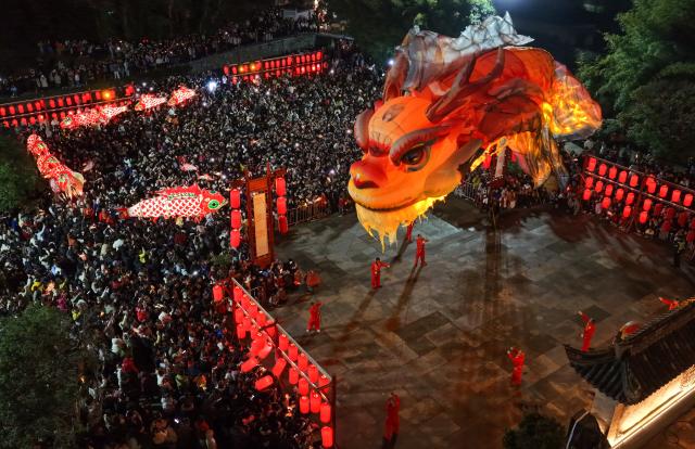 (260228) -- HUANGSHAN, Feb. 28, 2026 (Xinhua) -- An aerial drone photo taken on Feb. 27, 2026 shows people watching an Ao Fish lantern parade at the Tangmo ancient town in Huangshan City, east China's Anhui Province. The lantern parade was held here in celebration of the upcoming Lantern Festival on Friday, featuring the Ao Fish, a mythical Chinese creature with a dragon's head and a fish's body. (Photo by Shi Yalei/Xinhua)