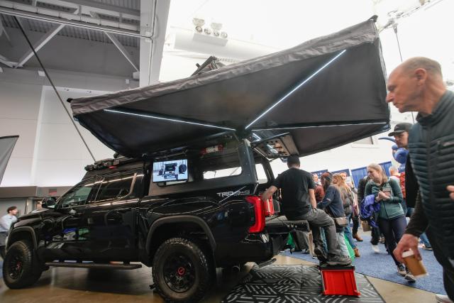 (260301) -- VANCOUVER, March 1, 2026 (Xinhua) -- Visitors look at a vehicle's rooftop tent at the 2026 Outdoor Adventure and Travel Show in Vancouver, British Columbia, Canada, on Feb. 28, 2026. The two-day annual event kicked off Saturday, with over 250 exhibitors showcasing the latest developments in camping gear, paddle sports equipment, outdoor clothing, scuba diving gear, and adventure travel experiences. (Photo by Liang Sen/Xinhua)
