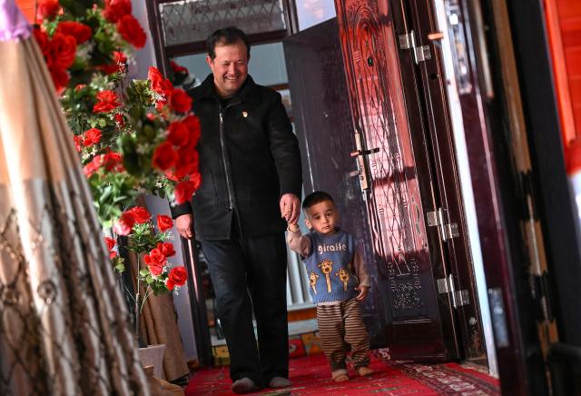 (260301) -- XINYUAN, March 1, 2026 (Xinhua) -- Musajan Khairat holds hand of a child at his home in Keregetas Village, Xinyuan County of Ili Kazak Autonomous Prefecture, northwest China's Xinjiang Uygur Autonomous Region, Feb. 9, 2026.
  Musajan Khaira, a villager of Keregetas Village of Xinyuan County, is a deputy to the National People's Congress (NPC). After graduating from junior high school, he learned blacksmithing and welding skills and runs a welding workshop. In addition to pursuing a better life for his own family, Musajan also taught welding skills to villagers for free, helping local people to increase their incomes.
  As an NPC deputy, Musajan consistently focuses on the demands of local people. In response to villagers' concerns about difficulties in farmland irrigation and road accessibility, he presented a suggestion on construction of high-standard farmland at a ravine area in Xinyuan County. With his efforts, a high-standard farmland construction project was launched and drip irrigation facilities were promoted, making it easier for farmers to cultivate the land and ensuring more stable income growth.
  Musajan keeps concentrating on high-quality development of rural areas. He presented suggestions such as advancing the reconstruction and expansion of local airport, upgrading county roads, and protecting wetland ecosystems, to promote rural development and improve local people's well-being. (Xinhua/Wang Fei)