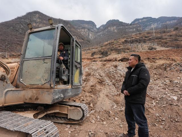 (260302) -- HANYUAN, March 2, 2026 (Xinhua) -- Zheng Wangchun (R) learns about the progress on village road construction in Gulu Village of Hanyuan County, southwest China's Sichuan Province, Jan. 29, 2026.
  Perched on a cliff at the entrance to the Dadu River Grand Canyon, Gulu Village in Sichuan Province was long isolated by poor transportation. The opening of a cableway in 2018 marked a turning point, cutting the journey from three to four hours down to just three to five minutes. 
  Zheng Wangchun is the head of the village committee and secretary of the Party committee of Gulu Village, and a deputy to the National People's Congress (NPC). Over the past years, Zheng has led villagers in developing a new path of integrated agricultural, cultural and tourism development, breathing new life into this Yi ethnic village. Villagers have opened homestays for visitors, and multiple scenic photo spots to enhance the visitor experience. At the same time, the village has expanded characteristic industries such as walnuts, Sichuan pepper, and goat farming. 
  Since taking office, Zheng has submitted suggestions including expanding internet access in rural areas and strengthening wildlife protection while minimizing its impact on farmers' livelihoods. "The smiles of villagers are the most valuable rewards for grassroots work," Zheng said. (Xinhua/Wang Xi)