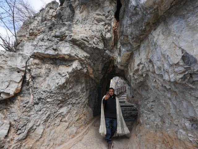 (260302) -- HANYUAN, March 2, 2026 (Xinhua) -- Zheng Wangchun takes videos for social media in Gulu Village of Hanyuan County, southwest China's Sichuan Province, Jan. 29, 2026.
  Perched on a cliff at the entrance to the Dadu River Grand Canyon, Gulu Village in Sichuan Province was long isolated by poor transportation. The opening of a cableway in 2018 marked a turning point, cutting the journey from three to four hours down to just three to five minutes. 
  Zheng Wangchun is the head of the village committee and secretary of the Party committee of Gulu Village, and a deputy to the National People's Congress (NPC). Over the past years, Zheng has led villagers in developing a new path of integrated agricultural, cultural and tourism development, breathing new life into this Yi ethnic village. Villagers have opened homestays for visitors, and multiple scenic photo spots to enhance the visitor experience. At the same time, the village has expanded characteristic industries such as walnuts, Sichuan pepper, and goat farming. 
  Since taking office, Zheng has submitted suggestions including expanding internet access in rural areas and strengthening wildlife protection while minimizing its impact on farmers' livelihoods. "The smiles of villagers are the most valuable rewards for grassroots work," Zheng said. (Xinhua/Wang Xi)