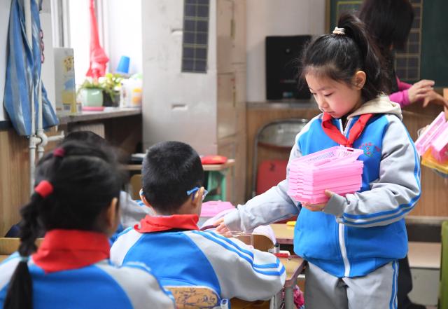 (260302) -- BEIJING, March 2, 2026 (Xinhua) -- A student helps distribute teaching aids at a primary school in Pinggu District of Beijing, capital of China, March 2, 2026. A new semester kicked off for primary and secondary schools in many parts of China on Monday. (Xinhua/Ren Chao)