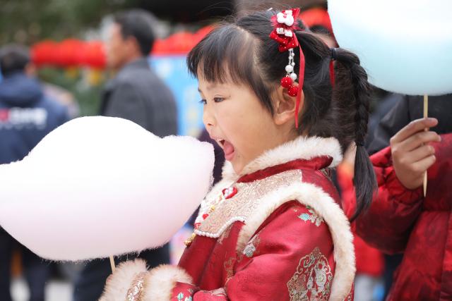 (260302) -- BEIJING, March 2, 2026 (Xinhua) -- A girl tastes cotton candy in Deqing County of Huzhou, east China's Zhejiang Province, Feb. 27, 2026.
  Various activities were held across China to celebrate the Lantern Festival, which falls on the fifteenth day of the first month of the Chinese lunar calendar, or March 3 this year. (Photo by Ni Lifang/Xinhua)