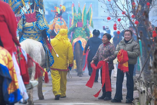 (260302) -- BAOJI, March 2, 2026 (Xinhua) -- Villagers greet a team of a Shehuo parade in Huanghuayu Village in Longxian County of Baoji City, northwest China's Shaanxi Province, March 2, 2026.
  Shehuo is a type of traditional Chinese folk art form. Longxian County held a special local Shehuo parade on Monday, which features performers on horseback adorned with simple yet exquisite facial make-up.
  The Shehuo parade is a long-standing and widely popular performance in rural China. It originated in ancient sacrificial ceremonies held to pray for good harvests about 2,000 years ago.
  Over time, as dance and song performances were incorporated, it gradually evolved into a folk custom staged during the Spring Festival and Lantern Festival, believed to ward off bad luck and usher in a fresh start for the new year.
  The Shehuo folk performance in Baoji was added to China's national intangible cultural heritage list in 2006. In recent years, the local Shehuo tradition in Longxian County has continued to thrive through ongoing inheritance and innovation. (Xinhua/Zou Jingyi)