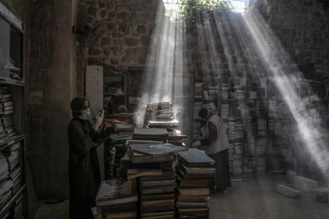 (260302) -- GAZA CITY, March 2, 2026 (Xinhua) -- Palestinian volunteers dust books as part of the initial rescue and restoration efforts for books and manuscripts destroyed during the Israeli bombardment of the Gaza Strip, inside the library of the Great Omari Mosque in Gaza City's Old City, on March 2, 2026. (Photo by Rizek Abdeljawad/Xinhua)