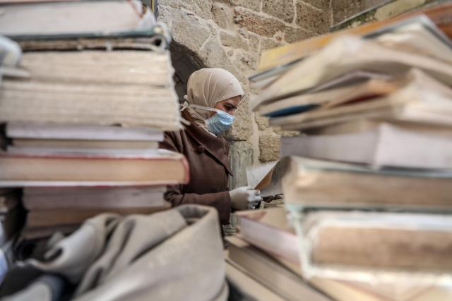 (260302) -- GAZA CITY, March 2, 2026 (Xinhua) -- A Palestinian volunteer dusts a book as part of the initial rescue and restoration efforts for books and manuscripts destroyed during the Israeli bombardment of the Gaza Strip, inside the library of the Great Omari Mosque in Gaza City's Old City, on March 2, 2026. (Photo by Rizek Abdeljawad/Xinhua)