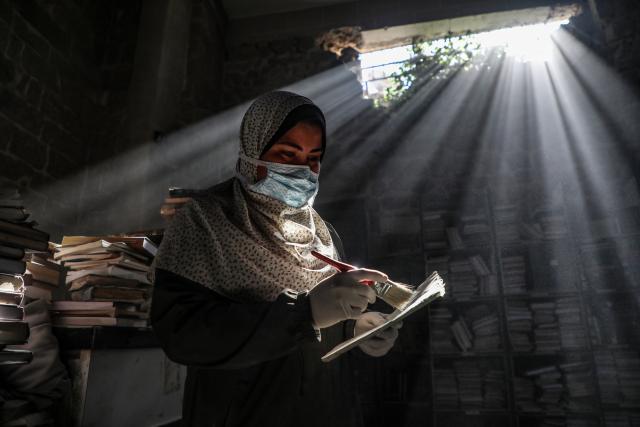 (260302) -- GAZA CITY, March 2, 2026 (Xinhua) -- A Palestinian volunteer dusts a book as part of the initial rescue and restoration efforts for books and manuscripts destroyed during the Israeli bombardment of the Gaza Strip, inside the library of the Great Omari Mosque in Gaza City's Old City, on March 2, 2026. (Photo by Rizek Abdeljawad/Xinhua)