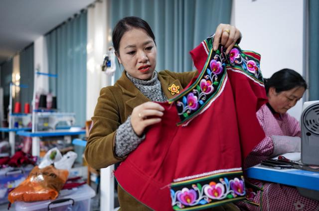 (260303) -- KUNMING, March 3, 2026 (Xinhua) -- Jin Ruirui checks a piece of Yi ethnic costume featuring handmade embroidery at her studio in Mouding County, southwest China's Yunnan Province, Feb. 9, 2026.
  Jin Ruirui, president of the county-level Yi embroidery association, has been dedicated to preserving the millennia-old craft while leading local embroiderers toward cultural prosperity and rural revitalization.
  With a history of more than 1,300 years, Yi embroidery features exquisite patterns and diverse stitching techniques, serving as an important carrier of ethnic Yi culture. 
  Over the years, Jin has helped more than 2,000 women find jobs. Through their efforts, the ancient craft has stepped out of the mountains and appeared on fashion week runways in cities such as Milan, New York and Paris. By blending with modern fashion design, it has repeatedly expanded into new markets and reached new audience.
  In 2023, Jin was elected a deputy to the National People's Congress (NPC). During her tenure, she has put forward proposals on issues such as the protection of Yi embroidery and related industrial development, employment, education, and healthcare.
  At this year's "two sessions," Jin will focus on the industrial growth of Yi embroidery, youth mental health and the prevention of juvenile crime. (Xinhua/Chen Xinbo)