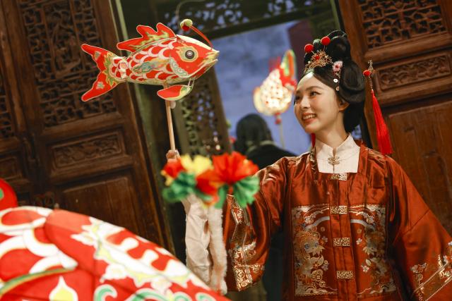 (260303) -- SHEXIAN, March 3, 2026 (Xinhua) -- A tourist holding a fish-shaped lantern poses for photos in Zhanqi Village, Shexian County, Huangshan City of east China's Anhui Province, Feb. 14, 2026.
  Local villagers in Shexian have the tradition to make fish-shaped lanterns, an intangible cultural heritage, on festival days to pray for harvest and good fortune. 
   The parade with fish-shaped lanterns is an important folk cultural activity held during traditional festivals.
   Nowadays, apart from parades with fish-shaped lanterns, local people have made efforts on developing new business forms related to the fish-shaped lantern including tourism and cultural and creative products. (Photo by Shi Yalei/Xinhua)