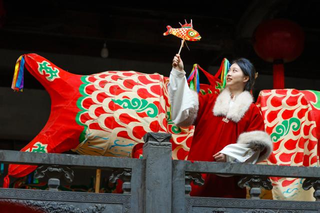 (260303) -- SHEXIAN, March 3, 2026 (Xinhua) -- A tourist holding a fish-shaped lantern poses for photos in Zhanqi Village, Shexian County, Huangshan City of east China's Anhui Province, Feb. 14, 2026.
  Local villagers in Shexian have the tradition to make fish-shaped lanterns, an intangible cultural heritage, on festival days to pray for harvest and good fortune. 
   The parade with fish-shaped lanterns is an important folk cultural activity held during traditional festivals.
   Nowadays, apart from parades with fish-shaped lanterns, local people have made efforts on developing new business forms related to the fish-shaped lantern including tourism and cultural and creative products. (Photo by Shi Yalei/Xinhua)