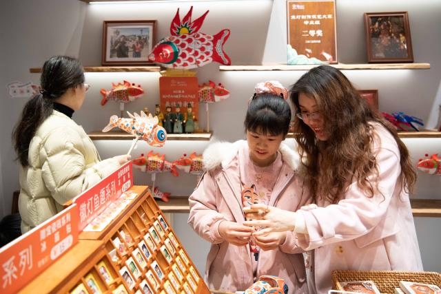 (260303) -- SHEXIAN, March 3, 2026 (Xinhua) -- Tourists shop at a souvenir shop themed on fish-shaped lanterns in Zhanqi Village, Shexian County, Huangshan City of east China's Anhui Province, March 1, 2026.
  Local villagers in Shexian have the tradition to make fish-shaped lanterns, an intangible cultural heritage, on festival days to pray for harvest and good fortune. 
   The parade with fish-shaped lanterns is an important folk cultural activity held during traditional festivals.
   Nowadays, apart from parades with fish-shaped lanterns, local people have made efforts on developing new business forms related to the fish-shaped lantern including tourism and cultural and creative products. (Xinhua/Zhang Duan)