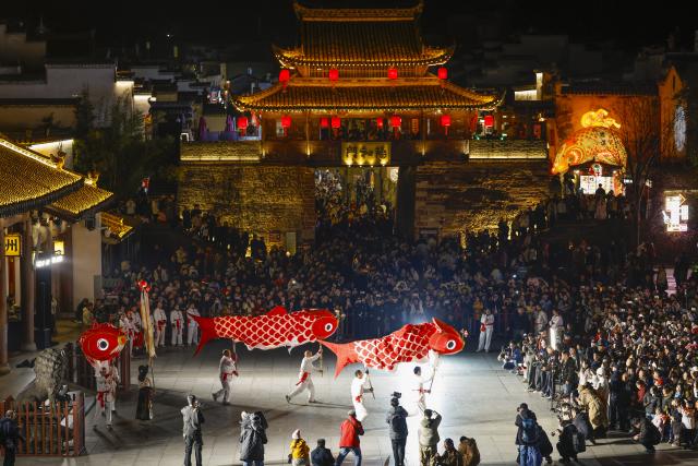 (260303) -- SHEXIAN, March 3, 2026 (Xinhua) -- People watch a fish-shaped lanterns performance in Shexian County, Huangshan City of east China's Anhui Province, Feb. 4, 2026.
  Local villagers in Shexian have the tradition to make fish-shaped lanterns, an intangible cultural heritage, on festival days to pray for harvest and good fortune. 
   The parade with fish-shaped lanterns is an important folk cultural activity held during traditional festivals.
   Nowadays, apart from parades with fish-shaped lanterns, local people have made efforts on developing new business forms related to the fish-shaped lantern including tourism and cultural and creative products. (Photo by Shi Yalei/Xinhua)