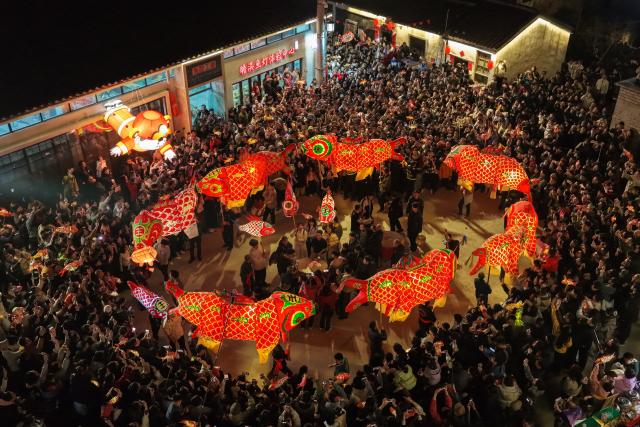 (260303) -- SHEXIAN, March 3, 2026 (Xinhua) -- People watch a fish-shaped lanterns parade in Shexian County, Huangshan City of east China's Anhui Province, Feb. 14, 2026.
  Local villagers in Shexian have the tradition to make fish-shaped lanterns, an intangible cultural heritage, on festival days to pray for harvest and good fortune. 
   The parade with fish-shaped lanterns is an important folk cultural activity held during traditional festivals.
   Nowadays, apart from parades with fish-shaped lanterns, local people have made efforts on developing new business forms related to the fish-shaped lantern including tourism and cultural and creative products. (Photo by Shi Yalei/Xinhua)