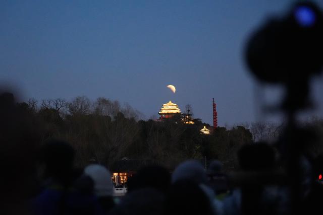(260303) -- BEIJING, March 3, 2026 (Xinhua) -- Tourists watch and photograph a total lunar eclipse at Beihai Park in Beijing, capital of China, March 3, 2026. Tuesday marked the Lantern Festival, which falls on the 15th day of the first month of the Chinese lunar calendar. This year's festival coincided with a total lunar eclipse. (Xinhua/Xie Han)