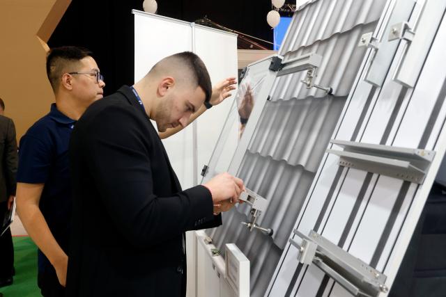 (260304) -- BUCHAREST, March 4, 2026 (Xinhua) -- Exhibitors check a solar panel mounting system during the first day of the Green Energy Expo & Romenvirotec event at Romexpo in Bucharest, Romania, March 3, 2026.
  The event is a regional platform for technologies in green energy, water, waste and sustainable cities. (Photo by Cristian Cristel/Xinhua)