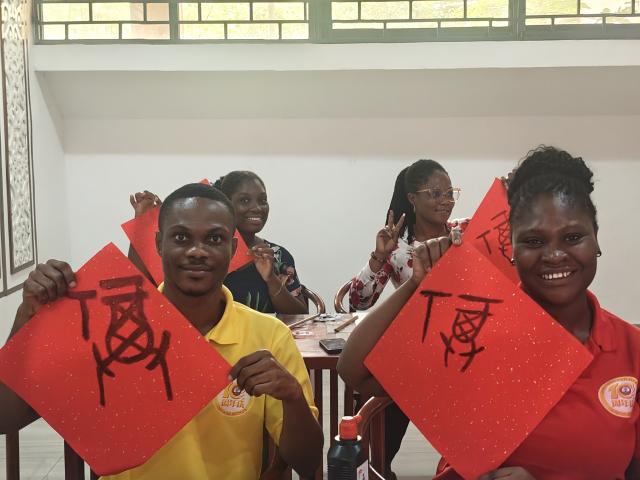 (260304) -- CAPE COAST, March 4, 2026 (Xinhua) -- Students showcase the oracle bone inscription version of the Chinese character "Fu," meaning "good fortune," they wrote during a Lantern Festival celebration event at the University of Cape Coast in Cape Coast, capital of Ghana's Central Region, March 3, 2026. The event was held jointly by the Confucius Institute and the Luban Workshop at the University of Cape Coast on Tuesday, attracting students to participate in activities such as guessing lantern riddles, writing blessing characters, making lanterns and tasting Yuanxiao, Chinese sweet glutinous rice dumplings for celebrating the Lantern Festival. (The Confucius Institute at the University of Cape Coast/Handout via Xinhua)