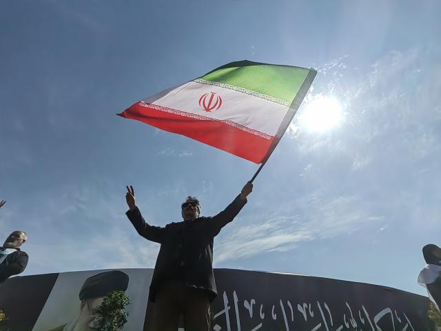 (260304) -- TEHRAN, March 4, 2026 (Xinhua) -- A man waves a national flag of Iran at Enghelab Square in Tehran, Iran, March 4, 2026. (Xinhua/Shadati)
