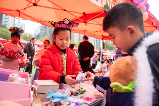 (260305) -- BEIJING, March 5, 2026 (Xinhua) -- A student (R) buys a toy during a charity sale at Lushan International Experimental Primary School in Changsha, central China's Hunan Province, March 4, 2026. The school held the sale on Wednesday. The fund collected will be used to support students with financial difficulties. (Xinhua/Chen Sihan)