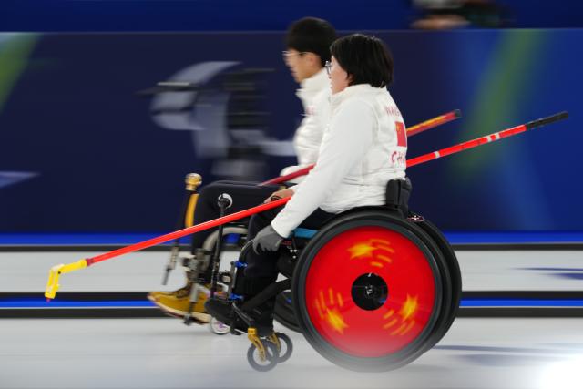(260305) -- CORTINA D'AMPEZZO, March 5, 2026 (Xinhua) -- Wang Meng (R) of China competes during the wheelchair curling mixed doubles round robin session 1 match between China and Japan at the Milan-Cortina 2026 Paralympic Winter Games in Cortina D'ampezzo, Italy, March 4, 2026. (Xinhua/Lian Yi)