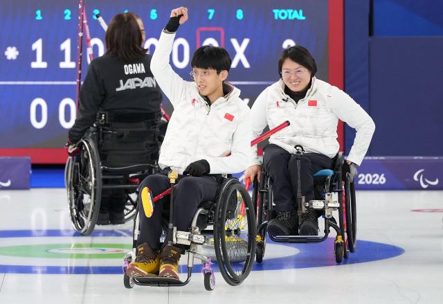 (260305) -- CORTINA D'AMPEZZO, March 5, 2026 (Xinhua) -- Yang Jinqiao (front L)  and Wang Meng of China celebrate victory after the wheelchair curling mixed doubles round robin session 1 match between China and Japan at the Milan-Cortina 2026 Paralympic Winter Games in Cortina D'ampezzo, Italy, March 4, 2026. (Xinhua/Hou Zhaokang)