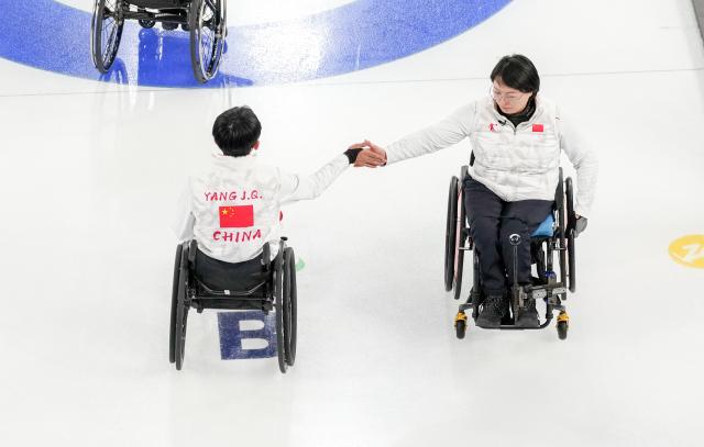 (260305) -- CORTINA D'AMPEZZO, March 5, 2026 (Xinhua) -- Wang Meng (R) and Yang Jinqiao of China react during the wheelchair curling mixed doubles round robin session 1 match between China and Japan at the Milan-Cortina 2026 Paralympic Winter Games in Cortina D'ampezzo, Italy, March 4, 2026. (Xinhua/Lian Zhen)