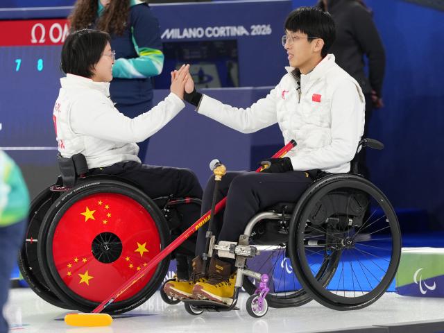 (260305) -- CORTINA D'AMPEZZO, March 5, 2026 (Xinhua) -- Wang Meng (L) and Yang Jinqiao of China celebrate during the wheelchair curling mixed doubles round robin session 1 match between China and Japan at the Milan-Cortina 2026 Paralympic Winter Games in Cortina D'ampezzo, Italy, March 4, 2026. (Xinhua/Lian Yi)
