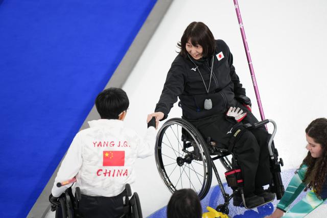 (260305) -- CORTINA D'AMPEZZO, March 5, 2026 (Xinhua) -- Yang Jinqiao of China (L) greets Ogawa Aki of Japan after the wheelchair curling mixed doubles round robin session 1 match between China and Japan at the Milan-Cortina 2026 Paralympic Winter Games in Cortina D'ampezzo, Italy, March 4, 2026. (Xinhua/Lian Zhen)