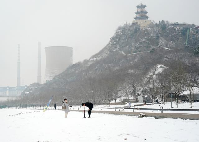 (260305) -- BEIJING, March 5, 2026 (Xinhua) -- Tourists visit the Shougang Park after a snowfall in Beijing, capital of China, March 5, 2026. Beijing has witnessed a spring snowfall from Wednesday to Thursday. (Xinhua/Zhang Chenlin)