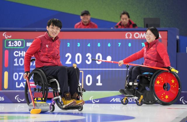 (260305) -- CORTINA D'AMPEZZO, March 5, 2026 (Xinhua) -- Wang Meng and Yang Jinqiao (L) of China react during the wheelchair curling mixed doubles round robin session 2 match between China and Latvia at the Milan-Cortina 2026 Paralympic Winter Games in Cortina D'ampezzo, Italy, March 5, 2026. (Xinhua/Hou Zhaokang)