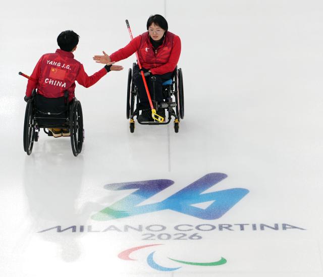 (260305) -- CORTINA D'AMPEZZO, March 5, 2026 (Xinhua) -- Wang Meng (R) of China celebrates with Yang Jinqiao during the wheelchair curling mixed doubles round robin session 2 match between China and Latvia at the Milan-Cortina 2026 Paralympic Winter Games in Cortina D'ampezzo, Italy, March 5, 2026. (Xinhua/Cai Yang)