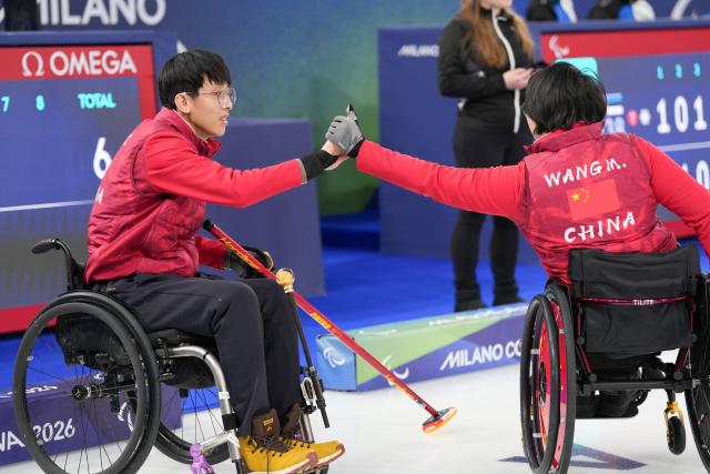 (260305) -- CORTINA D'AMPEZZO, March 5, 2026 (Xinhua) -- Wang Meng and Yang Jinqiao (L) of China react during the wheelchair curling mixed doubles round robin session 2 match between China and Latvia at the Milan-Cortina 2026 Paralympic Winter Games in Cortina D'ampezzo, Italy, March 5, 2026. (Xinhua/Lian Zhen)