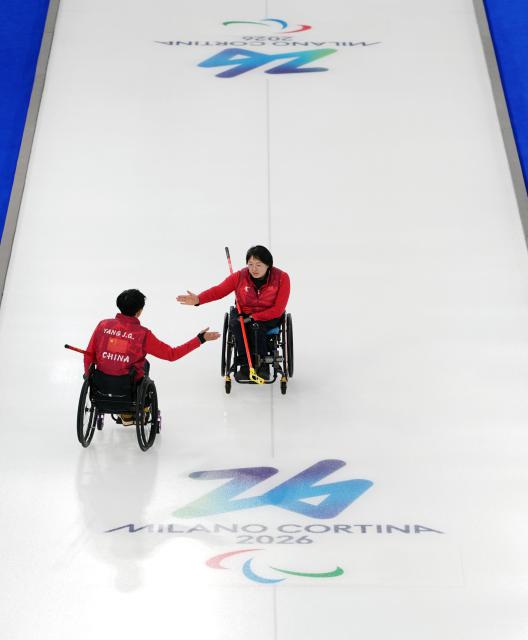 (260305) -- CORTINA D'AMPEZZO, March 5, 2026 (Xinhua) -- Wang Meng (R) of China celebrates with Yang Jinqiao during the wheelchair curling mixed doubles round robin session 2 match between China and Latvia at the Milan-Cortina 2026 Paralympic Winter Games in Cortina D'ampezzo, Italy, March 5, 2026. (Xinhua/Cai Yang)