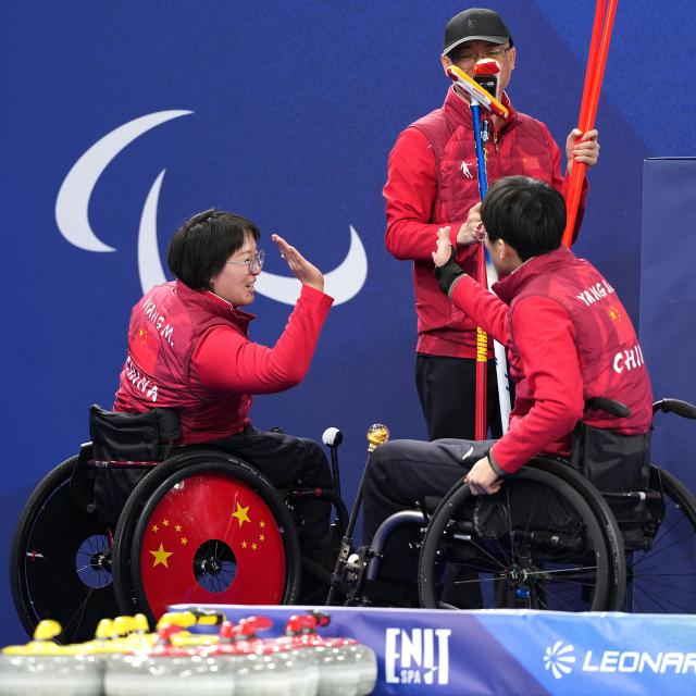 (260305) -- CORTINA D'AMPEZZO, March 5, 2026 (Xinhua) -- Wang Meng (L) and Yang Jinqiao of China celebrate victory after the wheelchair curling mixed doubles round robin session 2 match between China and Latvia at the Milan-Cortina 2026 Paralympic Winter Games in Cortina D'ampezzo, Italy, March 5, 2026. (Xinhua/Hou Zhaokang)
