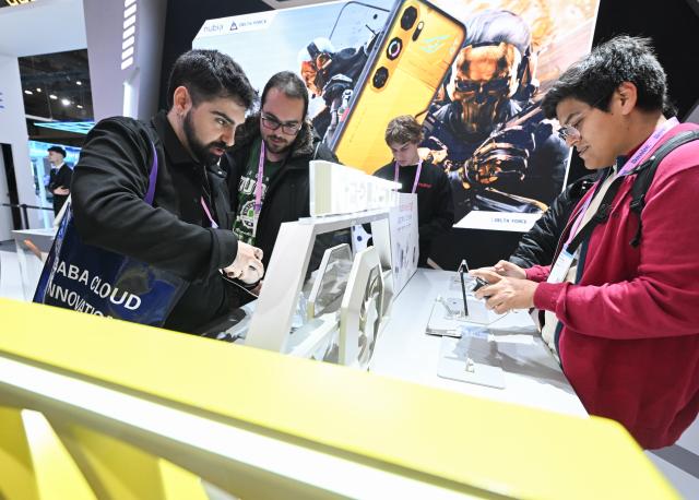 (260305) -- BARCELONA, March 5, 2026 (Xinhua) -- People try a gaming device from China's Nubia during the 2026 Mobile World Congress (MWC) in Barcelona, Spain, March 5, 2026. The 2026 MWC concluded here on Thursday. (Xinhua/Cheng Min)