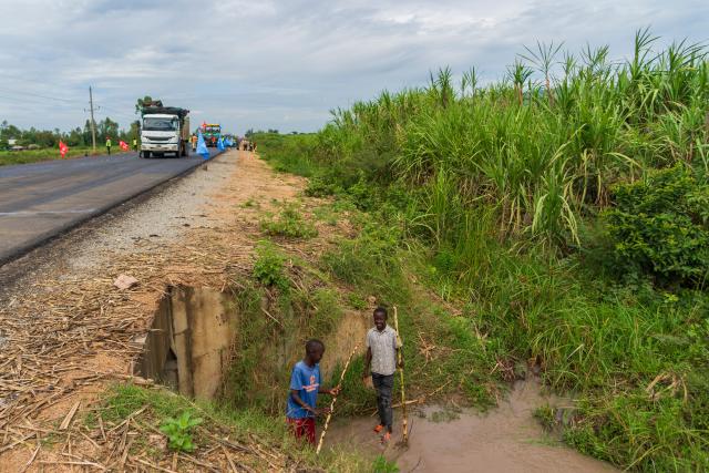 (260305) -- KISUMU, March 5, 2026 (Xinhua) -- Two boys wash sugarcane beside the construction site of the second section of the Kisumu-Muhoroni highway project built by Power Construction Corporation of China in a major sugarcane-producing area of Kisumu County, Kenya, on Feb. 27, 2026. Located in Kisumu County, a key economic and transport hub in western Kenya, the area is well known for sugarcane cultivation and sugar production. A road project undertaken by Power Construction Corporation of China is now bringing visible change to the region. (Xinhua/Xie Jianfei)