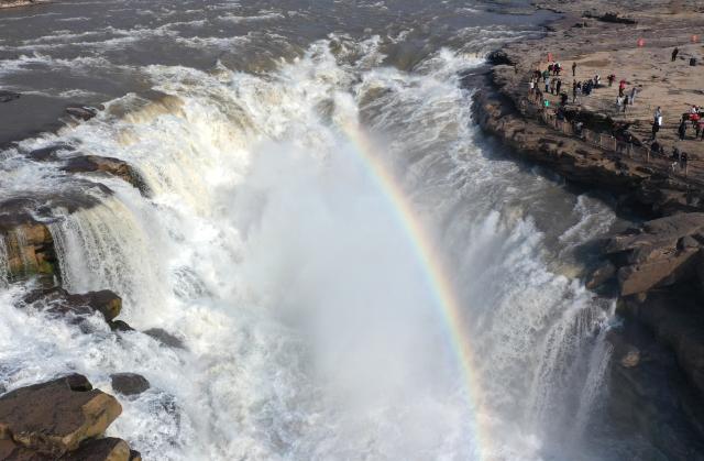(260306) -- BEIJING, March 6, 2026 (Xinhua) -- An aerial drone photo taken on March 5, 2026 shows tourists visiting the Yellow River's Hukou Waterfall in Jixian County, north China's Shanxi Province. (Xinhua/Lyu Guiming)